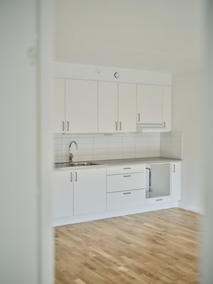 Inflyttningsklart kök med vita skåp, diskho och ljus trägolv