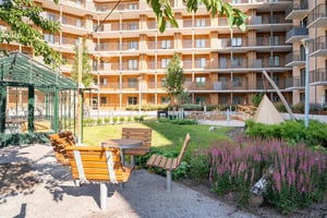 Innergård med sittplatser, växter och flerbostadshus med balkonger