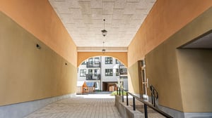 Ingång med valv till bostadsgård och moderna lägenheter i nybyggt bostadsområde