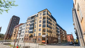 Nybyggda flerbostadshus med balkonger i ett modernt bostadsområde under klarblå himmel