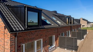 Inflyttningsklart radhus med rött tegel, svart tak och stora fönster
