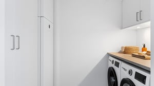 Badrum med tvättmaskin, torktumlare och vita förvaringsskåp