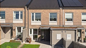 Radhus med entré, uteplats och grön trädgård i soligt väder