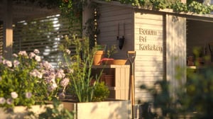 Trädgårdsbod med väggmonterade verktyg, blomlådor och skylt med texten Bonum Brf Korkeken