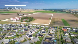 Flygbild över Fridsbo Ängar med bostadsområde, åkermark och markerad tomt för nybyggnation