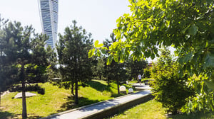Grön parkmiljö i Malmö med promenadstig, träd och hög modern byggnad i bakgrunden