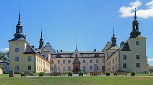 Tyresö slott med gula fasader, torn och innergård under blå himmel