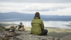 Kvinna som sitter och tittar ut över fjällvärlden