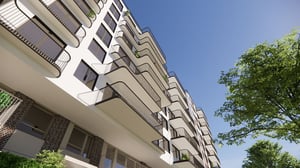 Flerbostadshus med balkonger och grönskande träd mot blå himmel