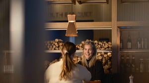 Två personer samtalar på restaurang med ved i bakgrunden