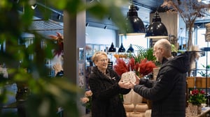Två personer håller i en glasvas i en presentbutik