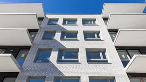 Flerbostadshus med vita balkonger och fönster i fasad