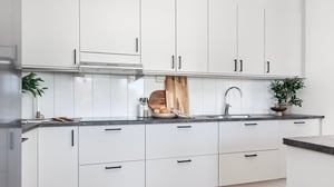 Lägenhet med modernt vitt kök, svarta detaljer och stilren arbetsbänk