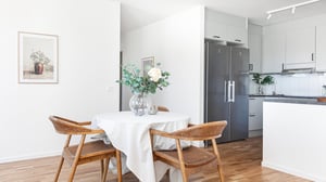 Kök och matplats med ljusa ytor, trästolar och matbord i modern bostad