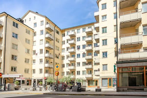 Flerbostadshus i ljus puts med torgliknande yta utanför porten