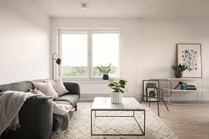 Inflyttningsklart vardagsrum med soffa, soffbord, fönster och ljusa väggar