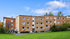Flerbostadshus i tegel med grön gräsmatta och blå himmel