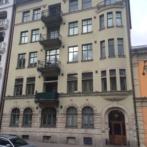 Flerfamiljshus med fasad i beige puts, balkonger och välvda fönster