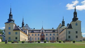 Tyresö slott med gula fasader, torn och innergård under blå himmel