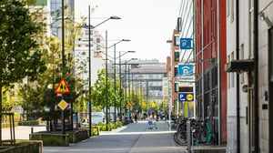 Stadsgata med cykelparkering, parkeringsskyltar och höga byggnader i ett modernt bostadsområde