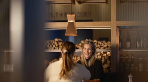 Två personer samtalar på restaurang med ved i bakgrunden