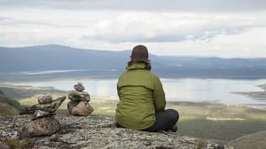 Kvinna som sitter och tittar ut över fjällvärlden