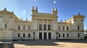 Lunds universitet med klassisk fasad och pelare, sedd från en öppen innergård under klar himmel