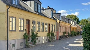 Klassisk radhuslänga i Lund med gula fasader och kullerstensgata i soligt väder