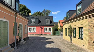 Charmig gårdsgata, i Lund, med färgglada hus och kullersten i soligt väder