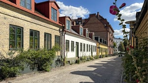 Brokig kullerstensgata i Lund med färgglada stadshus och gröna fasader i soligt väder