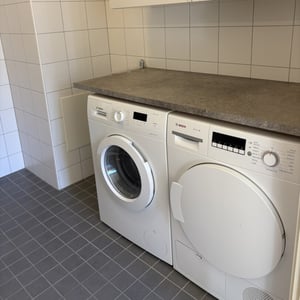 Tvättstuga med tvättmaskin och torktumlare under bänkskiva