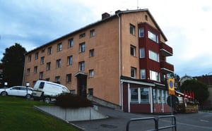 Flerbostadshus i beige och rött med butikslokal i bottenplan