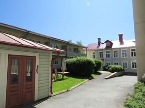 Flerbostadshus med innergård och gröna buskar under klarblå himmel