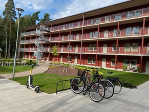 Rött flerbostadshus med balkonger och cyklar på gården