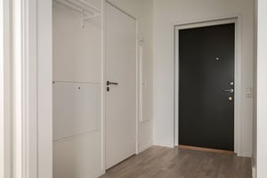 Inflyttningsklar lägenhet med vit hall, garderobsdörrar och svart ytterdörr