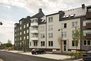 Exteriör av flerfamiljshus med parkerade bilar framför