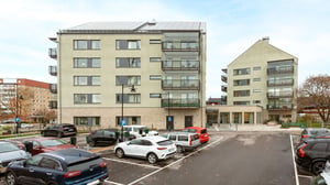 Bostadshus med parkeringsplats och flera bilar framför