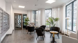 Ljus entréhall med postboxar, sittgrupp, stora fönster och växter