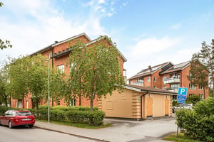 Förrådshuss coh träd framför flerbostadshus