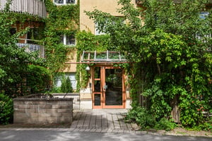 Entreport till flerbostadshus med grönska kring ingången