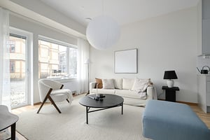 Vardagsrum med soffa, fåtölj, soffbord och stora fönster