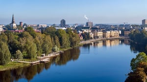 Utsikt över Karlstad med en bred älv, trädkantad strandpromenad och byggnader längs vattnet