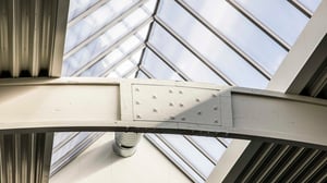 Takfönster med vita metallbalkar och takkupol i ett ljusgrått industriellt utrymme