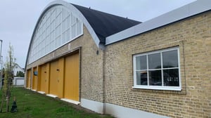 Exteriör av tegelbyggnad med välvt tak och gula portar i Helsingborg
