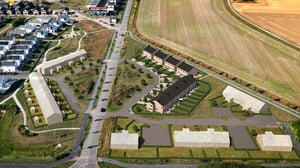 Illustration av ett bostadsområde med flerbostadshus, vägar och grönytor intill åkermark