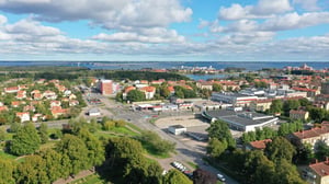 Flygvy över stad med bostadsområde, vägar, grönområden och hav i bakgrunden
