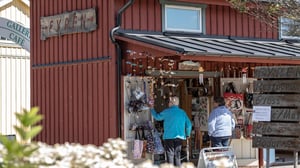 Två personer utanför en butik med skyltar och souvenirer vid entrén