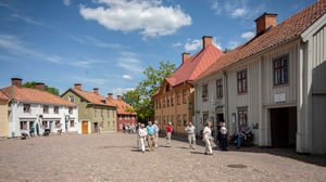Grupp av människor som promenerar på ett kullerstenslagt torg med färgglada äldre hus