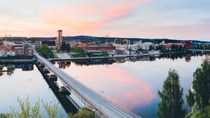 Vy över stad med bro över vatten i kvällsljus