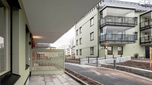 Nybyggda lägenhetshus med gröna fasader, glasbalkonger och asfaltgångar, omgivna av en nyanlagd gård